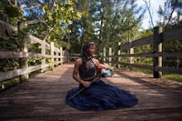 a woman in a blue dress sitting on a wooden bridge