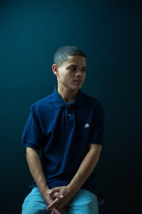 a young man in a blue polo shirt sitting on a chair