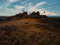 a car is parked on a hill in front of a house